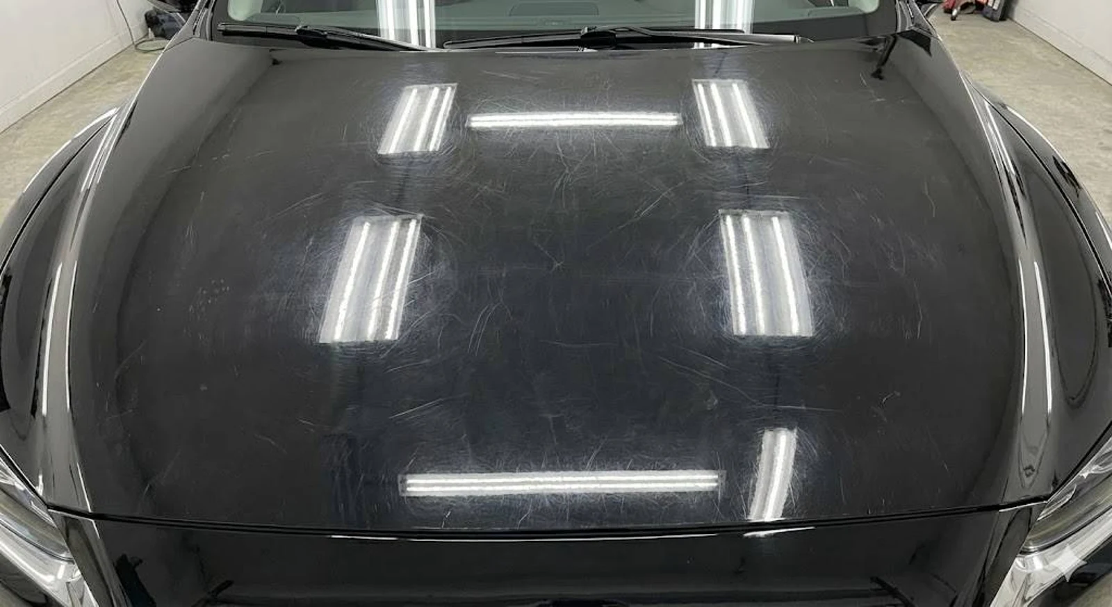 The same black hood covered in swirl marks and haze before paint correction