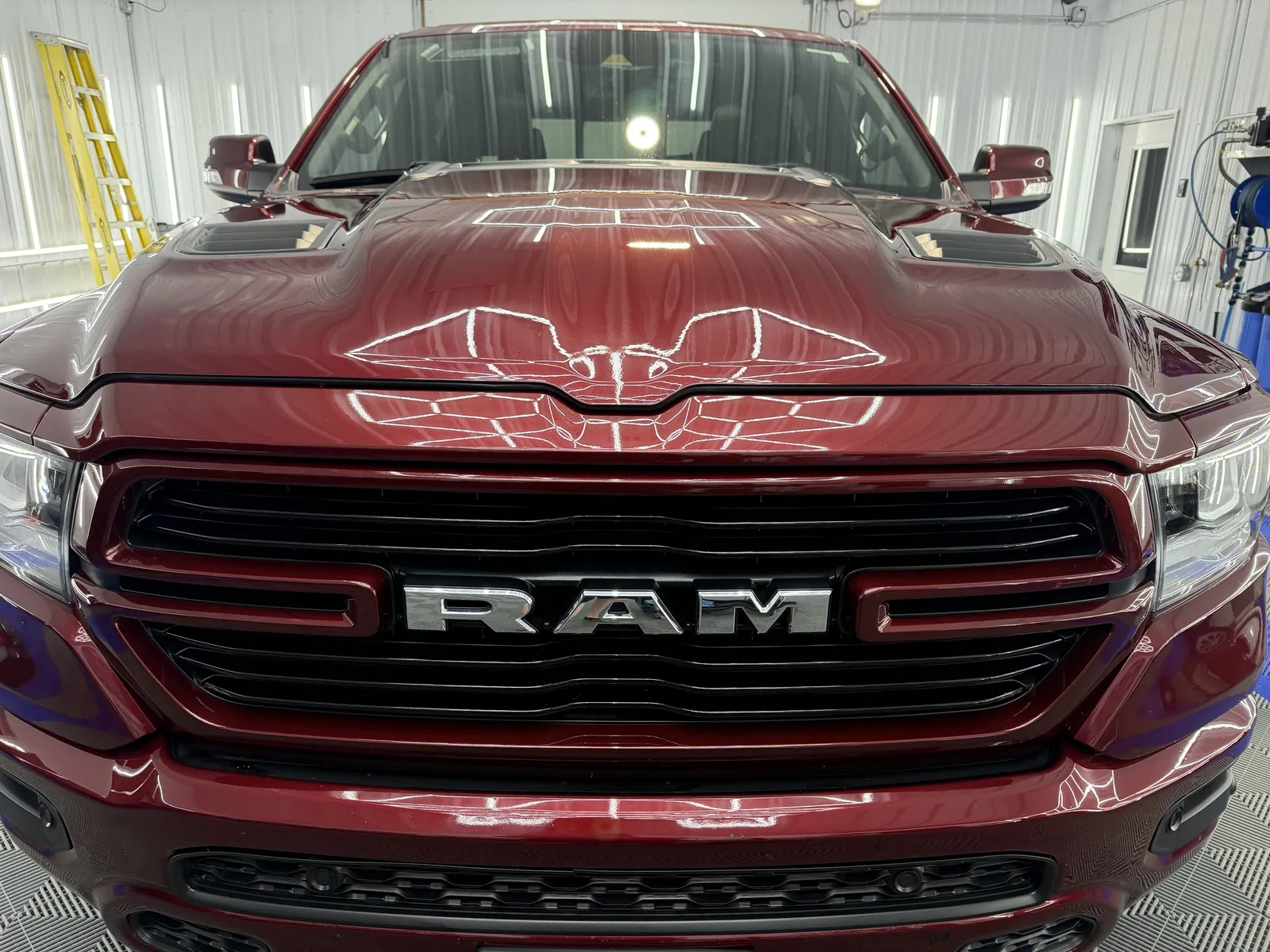 Hexagonal LED inspection lights reflected in the hood of a Ram pickup in the Porter’s Detailing bay in Grant Park