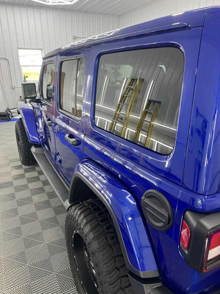 Blue Jeep hood with sharp reflections after machine polishing